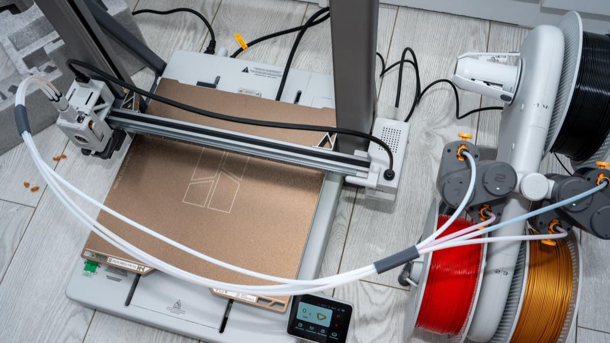 AMS Lite 4-spool feeder loaded with orange, red, white, and black filament