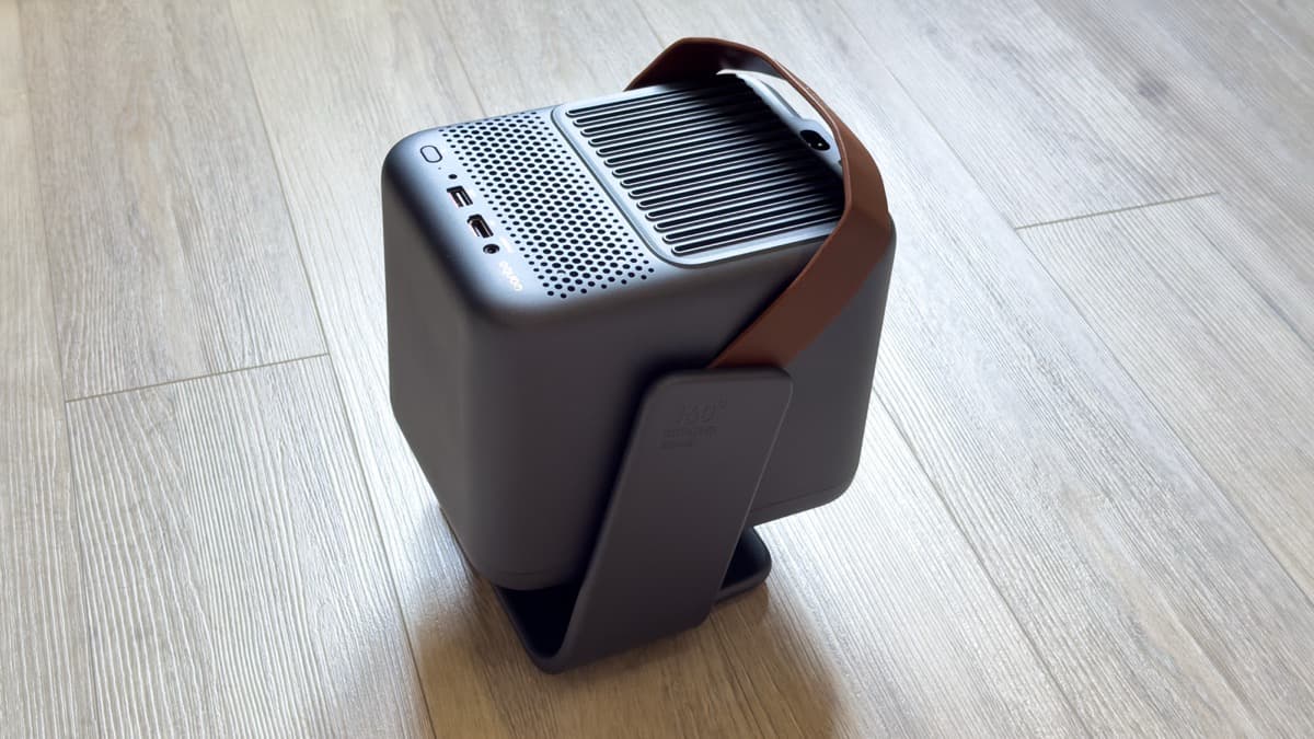 Wanbo ToGo Pro perched on hardwood flooring showing the integrated 360-degree rotating gimbal bracket and leather strap