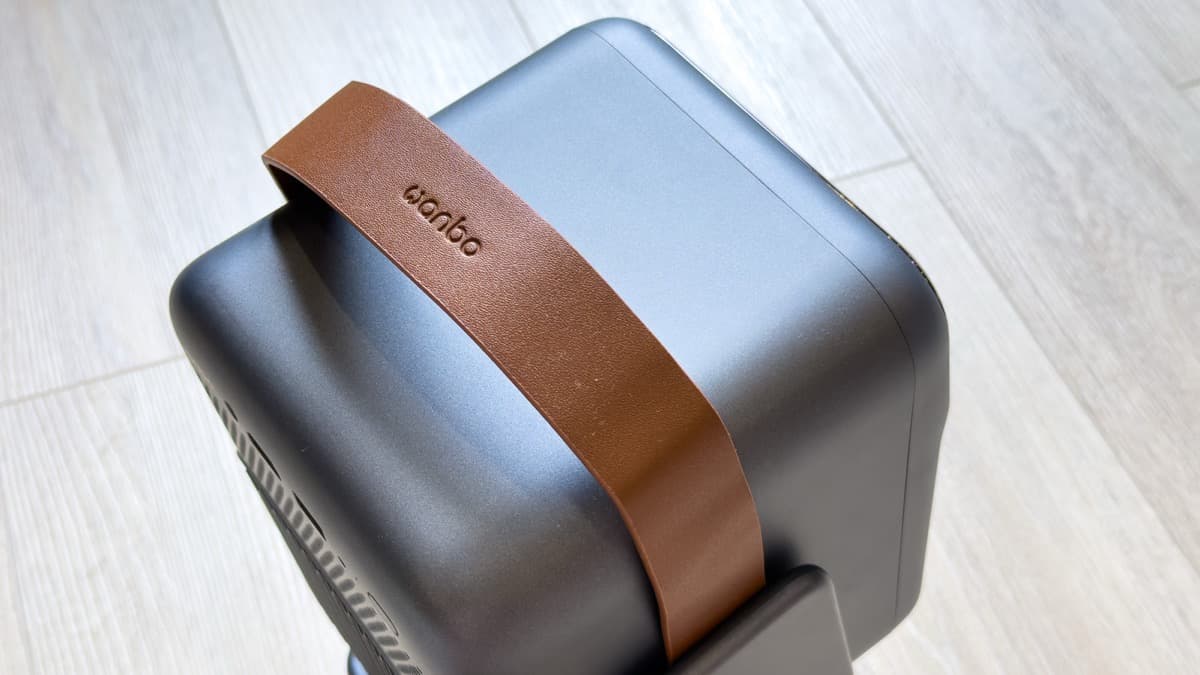 Macro detail of the saddle-brown synthetic leather handle with precision stitching and reinforced metal pivot studs