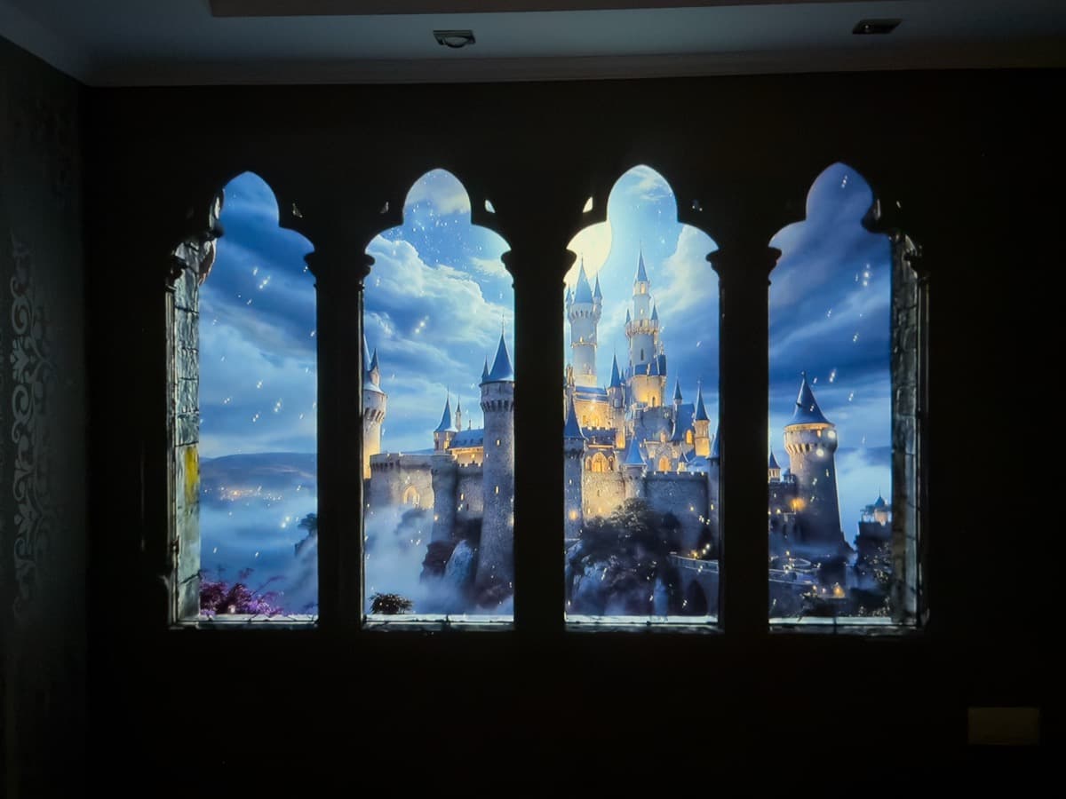 Real-world projection test: theatrical fairytale castle scene cast onto a dark wall, showing vibrant color saturation and deep shadows